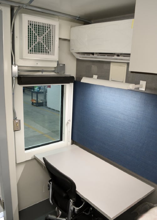 The interior of HATS unit for an American embassy, featuring a blast-rated window next to the desk